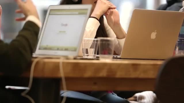 People working on laptops around a wooden table